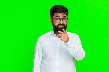 Hintli bir adam işaret parmağını ciddi bir ifadeyle sallar, birini uyarır ya da onaylamayan açık bir hareketle düzeltir. Arap adam yeşil krom anahtar arka planda izole edilmiş. Reddetme ve tavsiye gösteriyor.