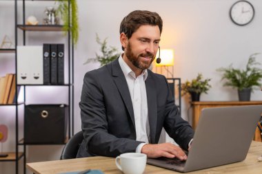 Merkez ofisteki orta yaşlı işadamı, çağrı merkezi operatörü olarak çalışıyor. Kulaklıklı, dinleyen ve dizüstü bilgisayarında müşterileri için çözümler üretiyor. Masadaki serbest çalışan adam kibarca konuşarak adımları doğruluyor ve notları kaydediyor..