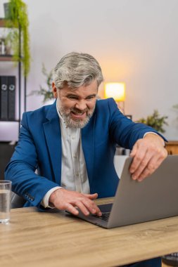 Merkez ofisteki orta yaşlı işadamı bilgisayarın donuk hata ekranına bakıyor ve kapak iç çekişini tekrar engelliyor. Masadaki serbest çalışan adam, kaybedilen ilerlemeyi telafi etmek için zamanı belirleyen yedek planı gözden geçiriyor..