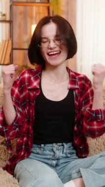 Genç bir kadın koltukta kameraya bakıyor, gülümsüyor ve başarısını kendinden emin bir vücut diliyle kutluyor. Kız kişisel zaferlerden hoşlanır, parlak gözlerle tepki verir ve neşeli enerjiyi canlandırır..