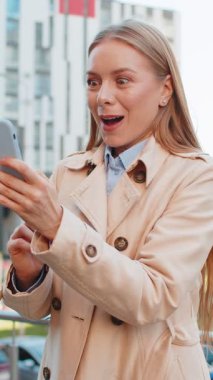 Cep telefonu kullanan Kafkas iş kadınının şehir merkezindeki akıllı telefon bahsini kazanan kadını şaşırtarak zafer başarısını kutlamasına şaşırdım. Şehir sokağında duran kız.