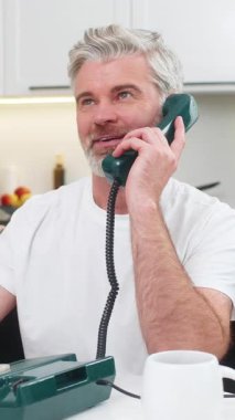 Evdeki orta yaşlı bir adam telefon hattını kaldırıyor nostaljiyle gülümsüyor ve koltuktaki masada sıcak bir merhaba diyor. Olgun adam cep telefonunu yakın paylaşıyor. Nazik sözler söylüyor. Sıcak bir ton ve kısa konuşmadan hoşlanıyor.