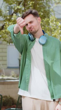 Hoşlanmamak. Kafkasyalı üzgün bir adam işaret dilini gösteriyor, hoşnutsuzluğunu, memnuniyetsizliğini, kötü işini, hatasını ifade ediyor. Şehrin güneşli caddesinde duran hoşnutsuz erkek..