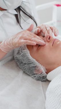 Deneyimli bir terapist kadına elleriyle masaj yaptırıyor. Salonda pürüzsüz, sağlıklı cilt bakımı. Göz altı torbaları iyileşiyor. Yüz fiziksel kozmetoloji oturumunda genç bir müşteri