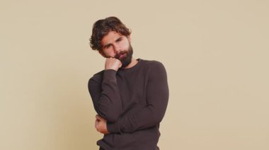 Sıkılmış, umursamaz Hintli adam ifadesi, sıkıcı hikayelerden bıkmış, iletişim konuşmalarıyla ilgilenmeyen, hoşnutsuz, ilgisiz. Bej renkli stüdyo arka planında izole edilmiş genç sakallı adam..