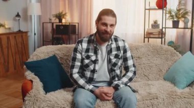 Genç adam evde oturmuş, neşeli sesiyle ve dostça el sallayarak bir anlığına 