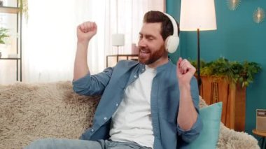 Evde kulaklıklı müzikten hoşlanan, ritmik dans eden ve elleri ritme göre hareket eden bir adam. Kanepede oturan beyaz adam ritmi hissediyor, sese dalmış, gevşemiş ve duygusal olarak meşgul.