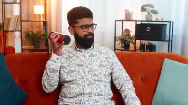 Hintli mutlu adam evinde koltukta oturuyor, akıllı telefondan en sevdiği müziği seçiyor ve taşınabilir hoparlörle çalıyor. Arap adam neşeyle dans ediyor, ritmin tadını çıkarıyor ve evde dinleniyor.