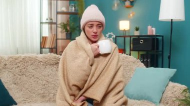 Evde hasta hisseden genç bir kadın sıcak bir battaniyeyle vücuduna sarılır. Sıcak bir şapka giyer ve serinlemek için yavaş yavaş sıcak çay içer. Kafkasyalı kız kanepede titriyor. Soğuk algınlığından nazikçe kurtulmayı umuyor.