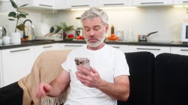 Evde orta yaşlı bir adam akıllı telefondan yapılan ödemeyi onaylıyor. Banka çekleri de onaylıyor. Kanepedeki olgun adam ekranda fişi görüyor. Gülümsüyor. Kolay nefes alıyor..