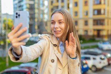 Olgun iş kadını blogcu akıllı telefondan selfie çekiyor, açık havada sosyal medya vlog 'u için abonelerle çevrimiçi video görüşmesi yapıyor. Şehir merkezindeki caddede duran kız.
