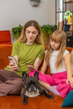 Evde Fransız bulldog 'u olan anne ve kız güvenli online kart ödemesi yapmayı öğreniyor. Kurallar ve sınırlar koyuyor. Kanepede köpekli kadın ve kız tamam jest yap güvenlik adımlarını at sahtekarlığı önle dersi onayla