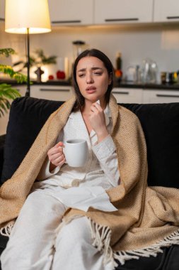 Geceleri evde battaniyenin altında boğaz ağrısı için sıcak çay ve ilaç yudumlayan genç bir kadın. Akşamları kanepede beyaz bir kız mendil kullanıyor. Hapşırıyor, ateşi azalıyor. Sessizce dinleniyor..