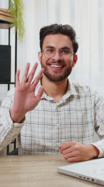 Hoş geldiniz. Mutlu Hintli genç işadamı el sallayarak selam veriyor. Birine hoş geldin diyor. İnternetteki Webinar, uzaktan konuşma. Ofiste dizüstü bilgisayarı olan serbest çalışan bir adam oturuyor..