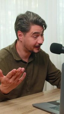 Evdeki orta yaşlı adam canlı video bloğu sunuyor. Laptop mikrofonuna sesleniyor. Seyirci etkileşimini destekliyor. Masadaki genç adam canlı konuşmalar yapıyor. İpuçlarını ekranda tutkuyla paylaşıyor.