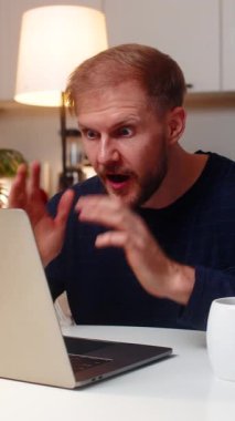 Evdeki genç adam dizüstü bilgisayarda onaylanmış uyarıyı görünce Grant kazandı. Sevinçten havalara uçuyor. Kutlamalar kazanır diyor. Masadaki kanepede oturan beyaz adam ikramiye hesabı online zafer gülümsemesi sakin ruh hali.