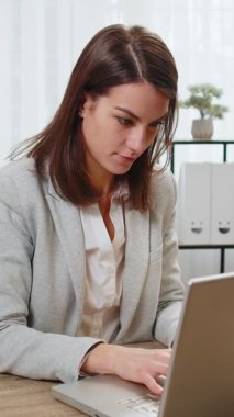 Mutlu iş kadını serbest çalışan, modern ofis çalışma masasında zafer kutlamaları yaptıktan sonra sandalyeye yaslanıyor. Resmi takım elbiseli kız evde ellerini başının arkasına koyup dinleniyor.