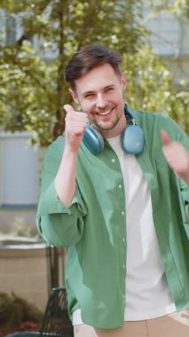 Gibi. Mutlu esmer erkek turist kameraya olumlu bakıyor. Olumlu yönde olumlu bir izlenim veriyor. Şehir caddesinde duran yetişkin bir adam. Şehir yaşam tarzları açık havada.