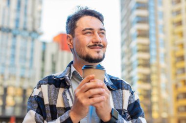 Kafkasyalı orta yaşlı mutlu bir adam sabah kahvesinin tadını çıkarıyor ve dışarıda gülümsüyor. Dinleniyorum, ara veriyorum. Şehir merkezindeki caddede dikilen ve kahve içen adam. Kasaba yaşam tarzları.