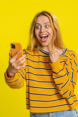 Mutlu Kafkasyalı genç kız akıllı telefon daktilo kullanıyor bağırarak evet de büyük ikramiye kazan iyi haber piyango hedefi başarıyı kutla, sarı ile oyun kazan