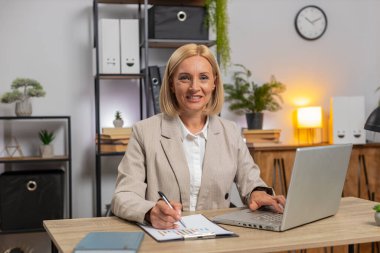 Finansal grafik belgeleriyle çalışan Kafkasyalı olgun serbest muhasebeci, çizelgeler için vergileri hesaplıyor ve ofis masasında raporlar hazırlıyor. Dizüstü bilgisayarda çalışan iş kadını, harcama bütçesi planlaması.