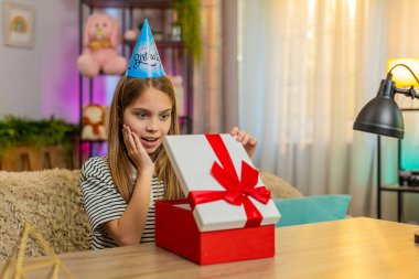 Masada oturan genç kız doğum gününü kutluyor ve sürpriz mutluluğu ifade eden bir hediye açıyor. Okul çocuğu heyecanla aldığı hediyeye sevinçle tepki veriyor.