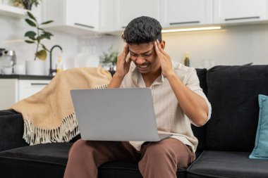 Evde oturan Hintli adam dizüstü bilgisayardaki inekler şakakları okşar baş ağrısını hisseder ve rahatlamak için nefesini yavaşlatır. Kanepedeki Arap adam kısa solunum egzersizi yapar gözlerini kapatır ve dizüstü bilgisayara sakince geri döner.