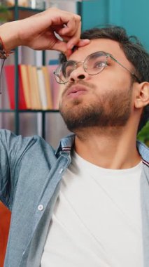 Hasta Hintli adam baş ağrısı problemini tedavi etmek için tapınakları ovuyor, tansiyon, migren, stres, ekşitme, evde yüksek tansiyon. Arap Hintli adam, kanepede kapalı bir odada.