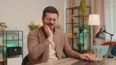 Kafkasyalı genç işadamı ofis masasında oturmuş diş ağrısının elleriyle dokunduğunu hissediyor diş hastalığından, diş eti hastalığından diş hastalığından diş hastalığından ve diş hastalıklarından dolayı acı dolu bir ifade..