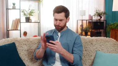 Evde orta yaşlı bir adam akıllı telefondan mesaj atarken gergin ve hayal kırıklığına uğramış hissediyor. Gergin, beyaz bir adam koltukta oturmuş, endişeyle önemli bir mesaj bekliyor.