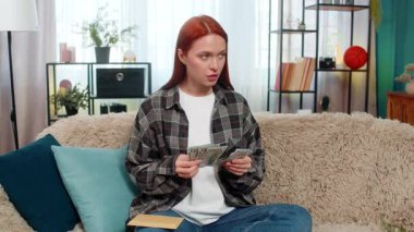 Evde para sayan genç bir kadın ve tatmin olmuş bir gülümsemeyle zarfa bir parça yerleştiriyor. Kafkasyalı kızıl saçlı kız kanepe planlama bütçesinde sorumlu ve duygusal olarak kendine güveniyor.