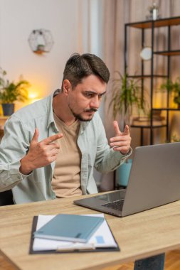 Ev ofisinin bilgisayarında çalışan serbest çalışan genç bir erkek çalışanla online iletişim videosu konuşması yapıyor, patron. Bilgisayar webcam 'ine bakan yönetici destek servisleri. Dikey.