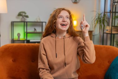 Evreka. Düşünceli, zeki, ilham verici kadın olumlu bir hareket yaptı. Yaratıcı bir plan ortaya attı. İyi bir fikirle heyecanlandı, ilham kaynağı oldu. Evdeki koltukta oturan kızıl saçlı kız..