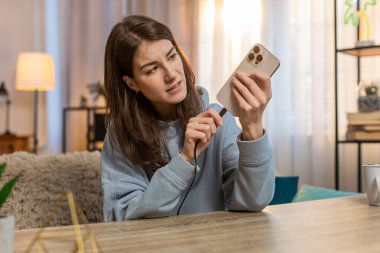 Kafkasyalı genç bir kadın akıllı telefona kablo bağlıyor ve şarj cihazı çalışmadığı için sürekli fişini çekiyor. Kız hayal kırıklığına uğramış görünüyor. Kablo kırılmış ve şarj edilemiyor..