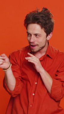 Sinsi, kurnaz, hilekar, hilekar, şakalar, eşek şakaları gibi sinsi, hilekar ve şeytani planları olan beyaz bir adam. Yakışıklı adam turuncu stüdyo geçmişinde izole edilmiş.