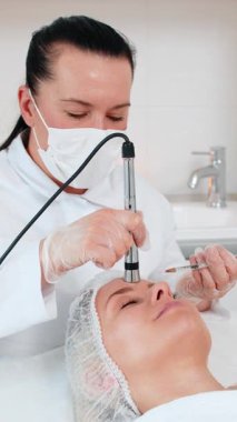 Enjeksiyonsuz mezoterapi ya da elektroporasyon. Güzellik doktoru, müşterilerine klinikte yetişkin kadın yüzü terapisi yaptırıyor. Kız cilt bakımı anti-yaş spa prosedürü. Estetik kozmetoloji.