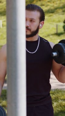 Spor kıyafetli atletik Lübnanlı adam kol ağırlığı kaldırıyor, halter egzersizleri yapıyor, kol kaslarını şişiriyor. Çocuk parkında. Spor, sağlık, spor, egzersiz. Kuvvet motivasyonu