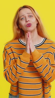 Lütfen, Tanrım yardım et. Bluz giymiş beyaz bir kadın dua ediyor, kameraya bakıyor ve dilek tutuyor, umut dolu bir ifadeyle soruyor, özür diliyor, meditasyon yapıyor. Sarı arka planda izole edilmiş yetişkin bir kız.