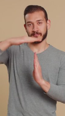 Lübnanlı genç bir adamın zaman aşımı jesti göstermesinden bıktım. Limit ya da dur işareti, baskı yok. Daha fazla zamana ihtiyacım var. Ortadoğulu çocuk stüdyo bej arka planında izole edilmiş.