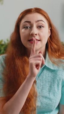 Sessiz olun lütfen. Kızıl saçlı genç bir kadının portresi işaret parmağını dudaklarına bastırıyor. Sessiz ol işareti yapıyor. Dedikodulara gizli bilgi verilmiyor. Modern ev dairesindeki kadın kanepede oturuyor.