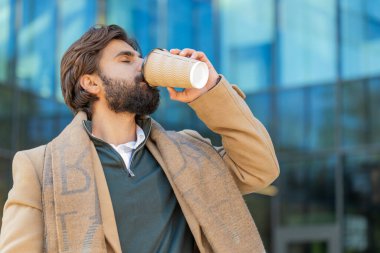 Mutlu Hintli genç adam sabah kahvesinin tadını çıkarıyor sıcak içecek ve dışarıda gülümsüyor. Dinleniyorum, ara veriyorum. Lübnanlı adam şehir merkezinde yürüyüp kahve içiyor. Dışarıdaki kasaba yaşam tarzları