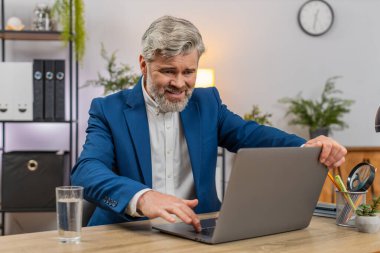 Merkez ofisteki orta yaşlı işadamı bilgisayarın donuk hata ekranına bakıyor ve kapak iç çekişini tekrar engelliyor. Masadaki serbest çalışan adam, kaybedilen ilerlemeyi telafi etmek için zamanı belirleyen yedek planı gözden geçiriyor..
