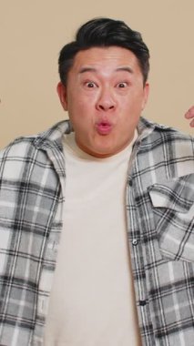 Aman Tanrım, vay canına. Heyecanlı Asyalı adam şaşkınlıkla el kaldırıyor. Büyük gözlerle kameraya bakıyor. Başarı başarısını kutlayan ani zaferin şokunu yaşıyor. Bej arka plandaki adam