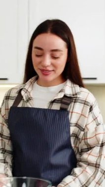 Genç kadın ketojenik diyet yemeği için mutfak tezgahındaki cam kasede sebze salatası karıştırıyor. Taze yeşillikler, brokoli ve ev yapımı yemek hazırlama, kız düşük karbonhidrat planı içeren sağlıklı beslenme konsepti.