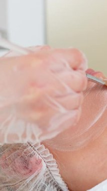 Enzim terapisi. Güzellik uzmanı, genç kadın yüzüne fırçayla nemlendirici, nemlendirici krem maske sürüyor. Kaplıcadaki kız cilt bakımı prosedürü. Yüz kozmetolojisi tedavisi