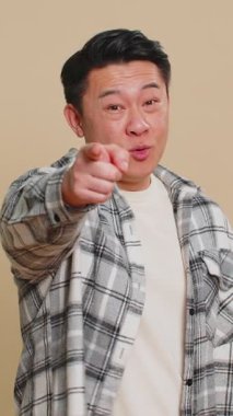 Hey sen! Mutlu Asyalı orta yaşlı adam heyecanlı bir şekilde gülümsüyor ve kamerayı ileri çeviriyor, şanslı oyun kazananını seçiyor, bu da sana müthiş bir terfi olduğunu gösteriyor. Çinli olgun adam bej arka planda izole edilmiş.