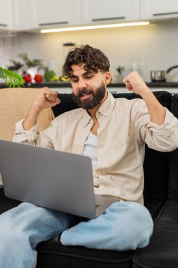 Evde dizüstü bilgisayarda çalışan Hintli adam serbest çalışmayı bitirdi ve ödeme başarısı mesajı gülümsemesi gördü. Kanepedeki Arap adam online müşteri bonusunu kutluyor. İyi gelir ödülünden memnun..