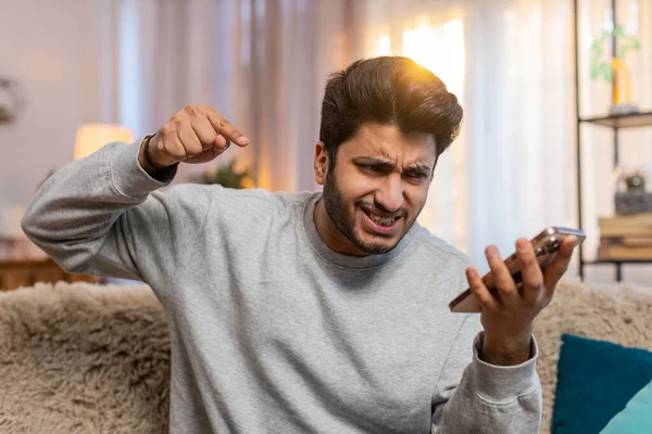 Kızgın kızgın sinirli Hintli genç adam hoparlör moduyla konuşurken tartışıyor sinirden bağırıyor. Arap, evdeki oturma odasındaki kanepede oturan memnun olmayan adamı gücendirdi..