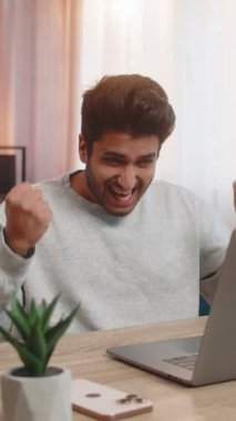 Genç Hintli adam dizüstü bilgisayar kullanıyor, e-postaları kontrol ediyor, beklenmedik bir şekilde önemli bir mektup alıyor, zaferi kutluyor. İspanyol adam sevinçle gülümsüyor, sevinçle el kaldırıyor, iyi haberlerle heyecanlanıyor..