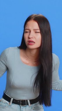 Kim var orada? Tık-tık. Heyecanlı genç bir kadın kapıyı çalıp kimin evde olduğunu soruyor, utanıyor, hiçbir fikri yok, bilgisiz ve kararsız. Stüdyo mavi arka planda tek başına kalmış bir kız.